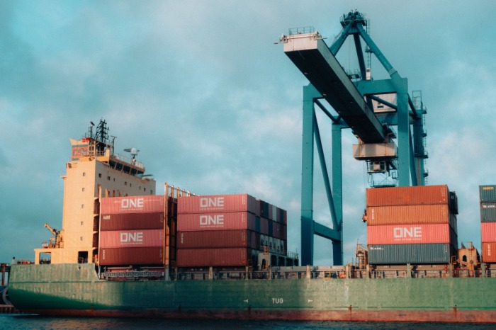 Buque portacontenedores amarrado en un puerto comercial siendo cargado por una grúa pórtico